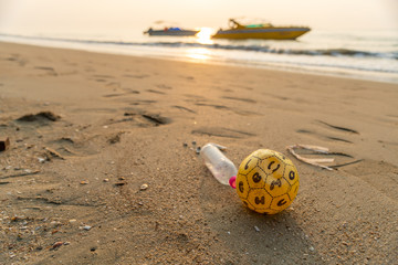 Obraz premium Plastic garbage on a beach with boats on background