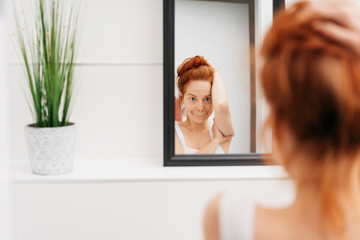 Cute young woman looking at herself in a mirror