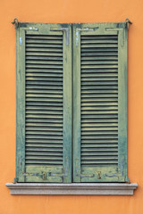 Fototapeta na wymiar Green window shutters on orange facade