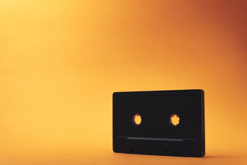 Black classic magnetic cassette tape on a orange background.