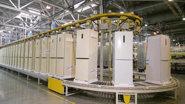 row of domestic fridges transported by conveyor at plant