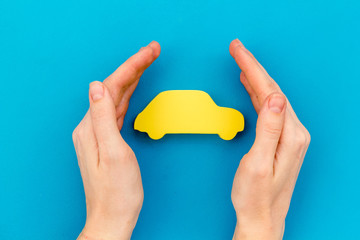 Car insurance concept with car in hands on blue background top view mockup