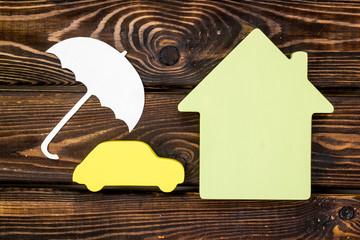 Car insurance concept with car, house and umbrella toys on wooden background top view mockup