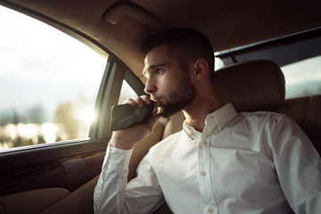 Man looking away while sitting on the back seat of a car, businessman in taxi