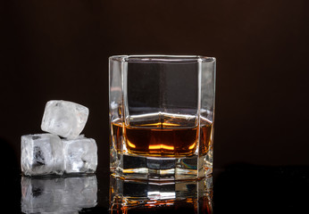 hexagonal glass of whiskey with ice on a dark background and a number of real ice cubes