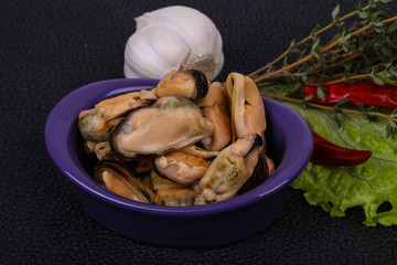 Pickled mussels in the bowl served pepper, garlic and salad