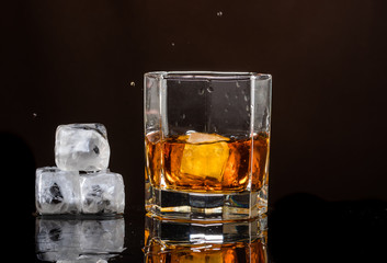 hexagonal glass of whiskey with ice on a dark background and a number of real ice cubes