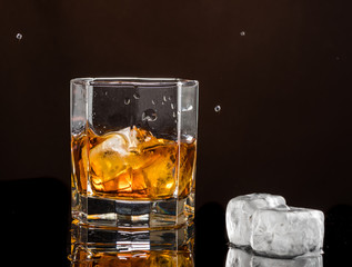 hexagonal glass of whiskey with ice on a dark background and a number of real ice cubes