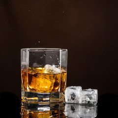 hexagonal glass of whiskey with ice on a dark background and a number of real ice cubes