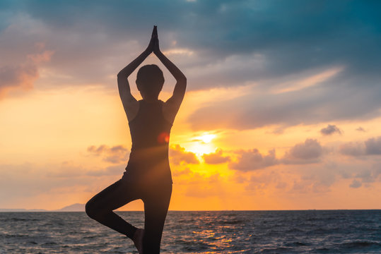 silhouette of woman practicing yoga on the beach at sunset © 2B