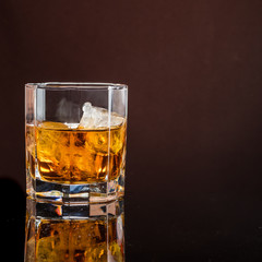 hexagonal glass of whiskey with ice on a dark background and a number of real ice cubes