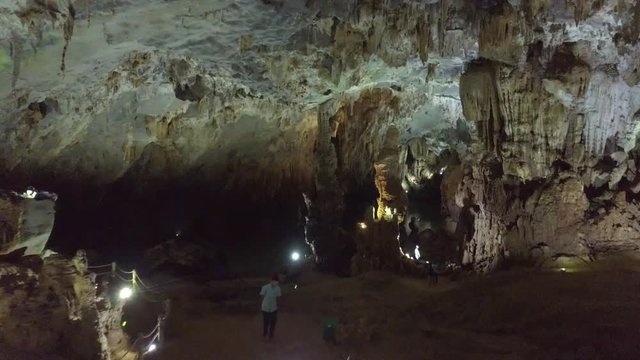 aerial motion inside beautiful ancient cave with stalactites and stalagmites lit by powerful projectors