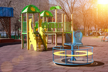 Children's playground in the courtyard of a multistory building. Multi-colored swings and slides are installed.