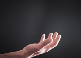 Human hand on dark background.