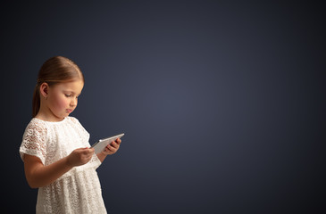 Adorable little girl using tablet with dark empty space
