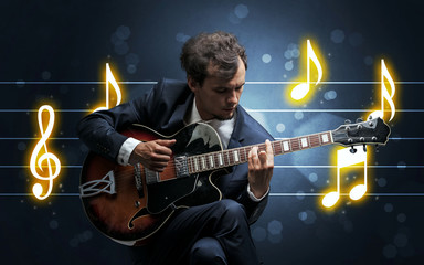 Young handsome guitarist playing with music sheet background