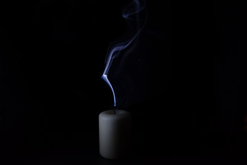 Blue smoke from an extinguished candle on a black background