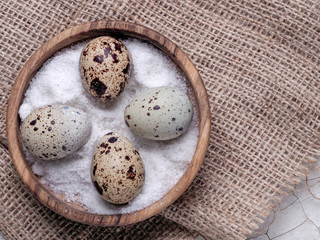 Fototapeta na wymiar Four quail eggs in a wooden plate on a burlap. Easter set of useful food from poultry. Environmentally friendly product for children and adults.
