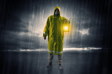 Fototapeta na wymiar Raincoated man walking in storm with glowing lantern in his hand 