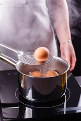 young woman in an gray apron boiled eggs