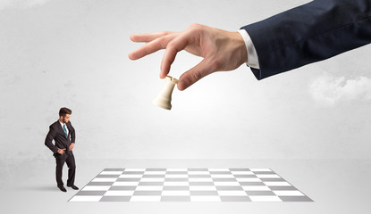 Little businessman thinking about chess strategy with a big hand concept
