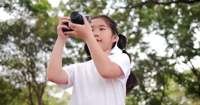 Asian little girl enjoy when using camera at park.