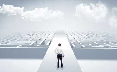 Businessman going straight ahead on a wide road between mazes
