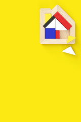 Fototapeta na wymiar House-shaped puzzle placed in the upper right of vertical format. Two pieces are off. Yellow background with copy space, flat layout.