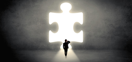 Businessman  standing and looking to a big puzzle piece
