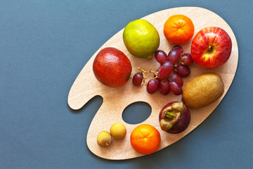 Bright tropical ripe juicy fruits  on a cutting board in the form of an artistic palette on a gray-blue table. Edible background. Low-calorie diet. Top view, flat lay style, copy space