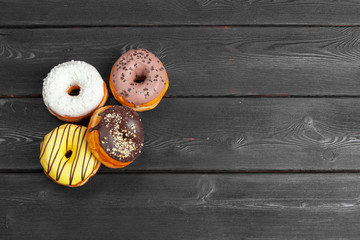 Colorful fresh donuts on dark black wooden surface