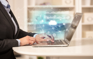 Business woman in homey environment using laptop with cloud technology concept
