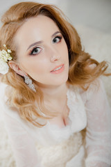Beautiful girl with blond hair in a bright room is lying on the floor. Bride lying looking at the camera and smiling