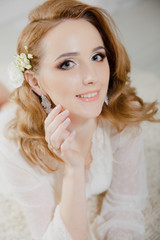 Beautiful girl with blond hair in a bright room is lying on the floor. Bride lying looking at the camera and smiling