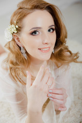 Beautiful girl with blond hair in a bright room is lying on the floor. Bride lying looking at the camera and smiling