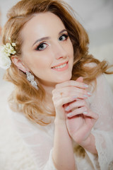 Beautiful girl with blond hair in a bright room is lying on the floor. Bride lying looking at the camera and smiling