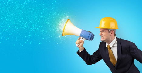 Fototapeta premium Young architect constructor yelling with megaphone and sparkling sounds 