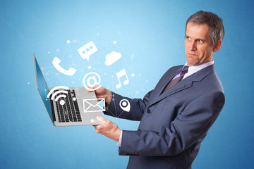 Man holding laptop with online services symbols
