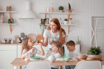 Mom and children are sitting at the table in the kitchen