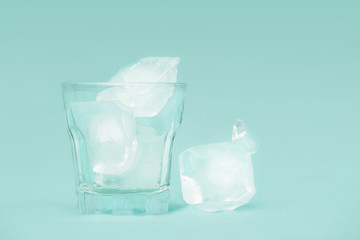 Ice cubes in a shot glass on green background