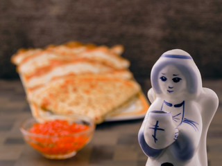 Four ruddy pancake neatly on the plate bowl with red caviar. Next figure of an angel holding a Church candle. Nutritious healthy food with vitamins and minerals. Breakfast, lunch or dinner 