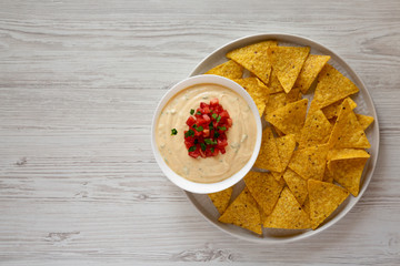 Homemade cheesy dip in a bowl, yellow tortilla chips, top view. Flat lay, overhead, from above. Copy space.