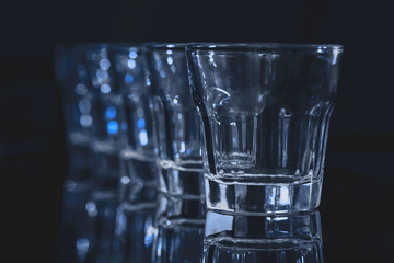 Arrangement of five shot glasses on black background