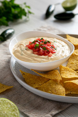 Homemade cheesy dip, yellow tortilla chips, side view. Close-up.
