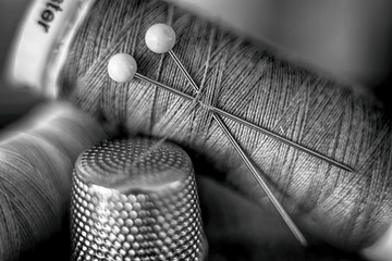 Black and white image of cotton reel, thread, pins and thimble