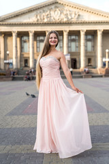 Fototapeta premium Urban portrait of young, slim, beautiful model in pink dress