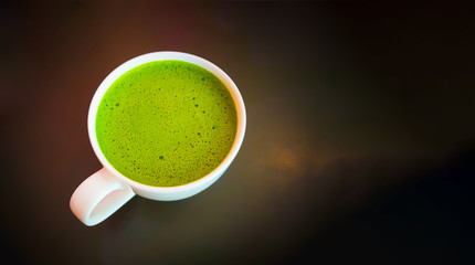 Hot green tea latte in a white cup on a wooden table with copy space-Image.