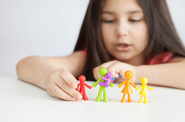 Obraz na płótnie Canvas Happy traditional family figurines. A small child plays with colored plastic figures. Mom, dad, brother, sister, siblings. Family symbol. Adoption. Full family. Face out of focus.