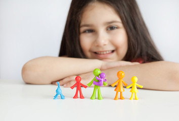 Happy traditional family figurines. A small child plays with colored plastic figures. Mom, dad, brother, sister, siblings. Family symbol. Adoption. Full family. Face out of focus.