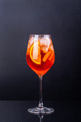 Aperol spritz cocktail in glass on black reflection background.